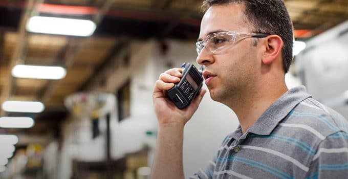 man wearing safety glasses using a two way radio