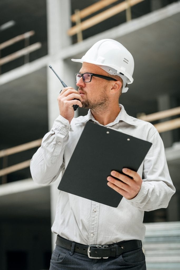 worker wearing a safety vest and hard hat using a two way radio